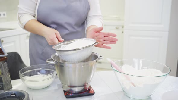 Cook Sifts the Flour Through a Sieve to Prepare Dough in a Mixer Bowl on Scale