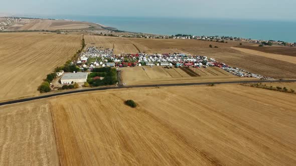 Drone Shot with Top View of Agricultural Expo Fair on Yellow Fields of Farm Lands with Open Blue Sky