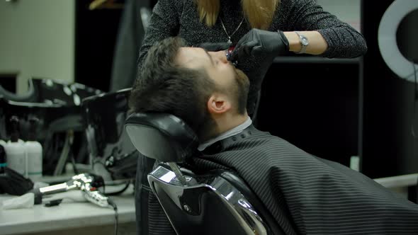 Female Barber Trimming Mustache of Man
