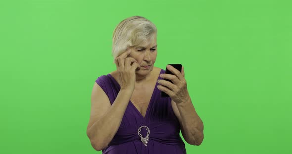 An Elderly Woman Works on a Smartphone. Old Grandmother Smiles. Chroma Key