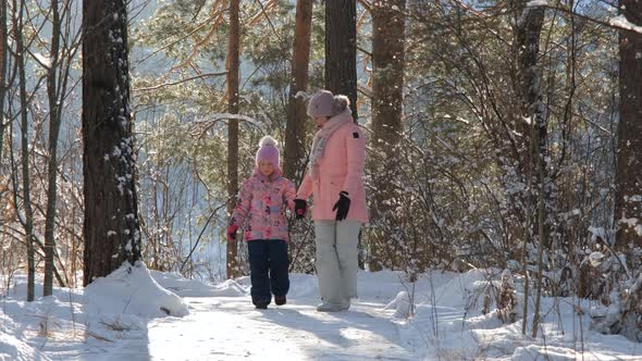 Mother with Daughter Walking in Winter Forest