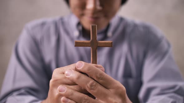 A young Asian Christian man praying to Jesus Christ in a church. alt