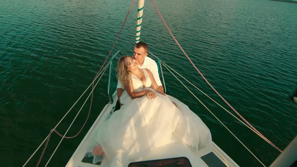 The Bride and Groom Are Sitting on a Yacht. Bride with Closed Eyes