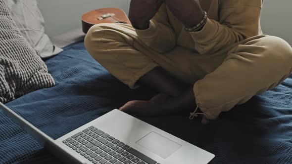 Black Man Sitting on Bed and Chatting on Online Call on Laptop