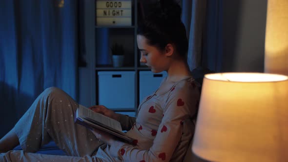 Teenage Girl Reading Book in Bed at Night