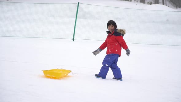 Cute Asian Child Playing Sled On Snow