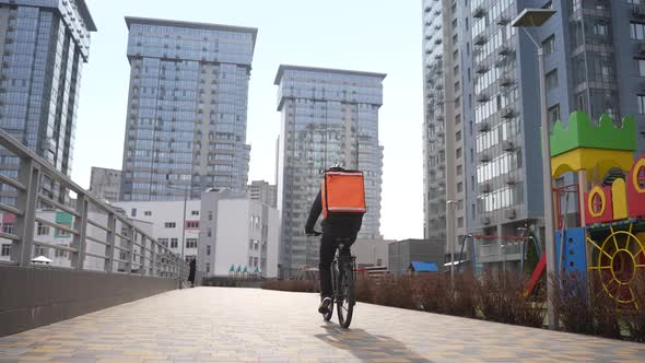 Food Delivery Man Riding Bike Along Courtyard Path