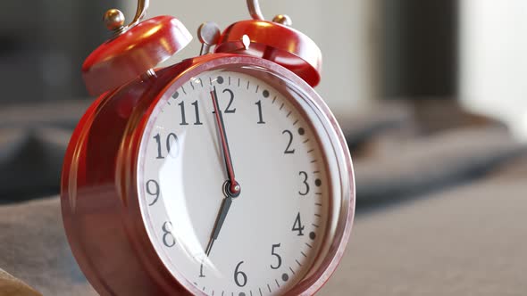 Old vintage red alarm clock standing on a bed sheet. Bells ring on time. 4KHD