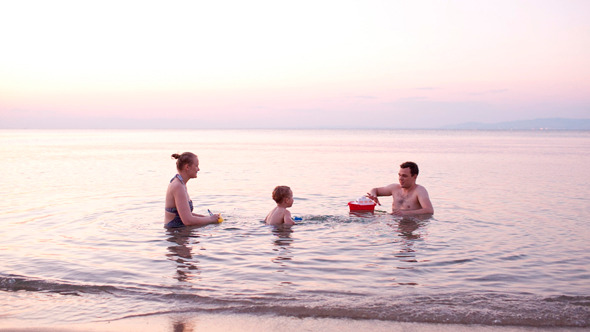 Young Family Playing Red toy Boat at Sunset