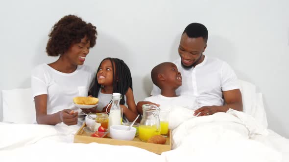 Happy family having breakfast together on bed