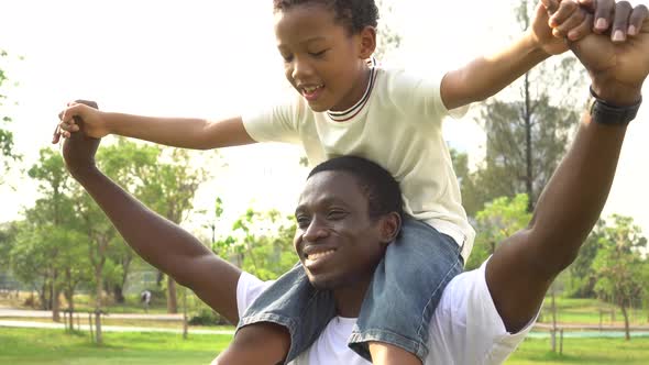 Happy African American Father and Son Piggyback in Outdoor Park