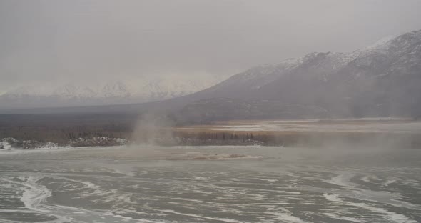 Aerial helicopter shot, fly over Alaskan mountain ridge to reveal valley and mountain range in dista