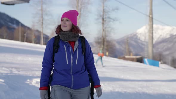 A Woman in a Warm Winter Suit Walks Along a Winter Street of the City Against the Background of Ski