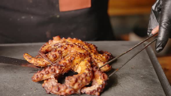 Male chef presenting a perfectly cooked and tenderized octopus with golden brown crisp surface by ro