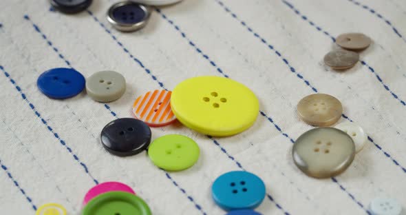 Colorful Buttons Falling on Striped Fabric Closeup