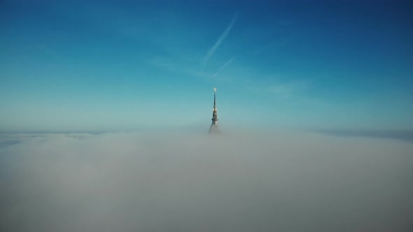 Drone Flying To and Above Mont Saint Michel Golden Castle Spire Covered By Thick Fog Mist Clouds in