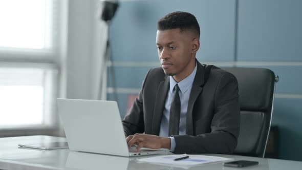 African Businessman Shaking Head as No Sign while using Laptop in Office