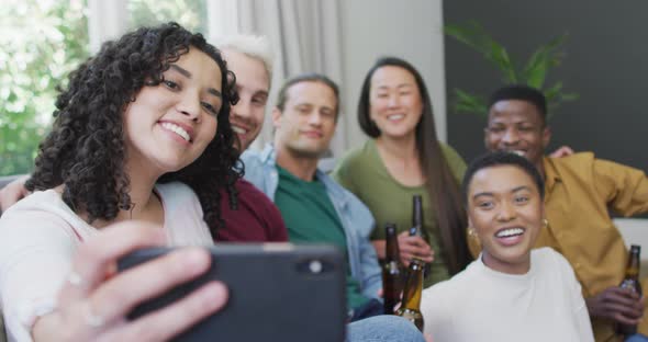 Diverse group of happy male and female friends smiling and taking selfie in living room