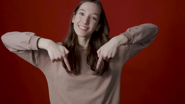 A Positive Young Woman Points Her Fingers Down Indicating a Spot for your Advertisement