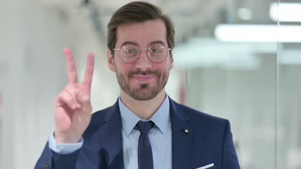 Portrait of Successful Young Businessman Showing Victory Sign with Hand