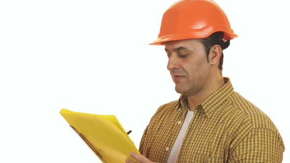 Mature Foreman Builder in a Hardhat Making Notes on Clipboard