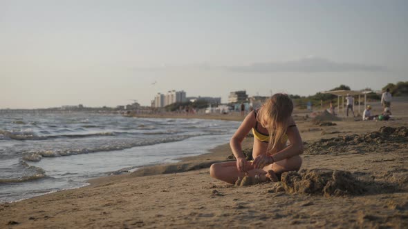 Little Girl Playing with Sand on Beach. Enjoying a Lovely Vacation.