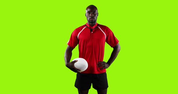 Professional Rugby Player Standing and Holding a Ball on Green Background
