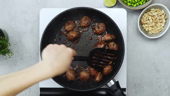 Woman cooking meatballs on frying pan with oil