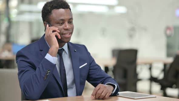 African Businessman Talking on Smartphone in Modern Office