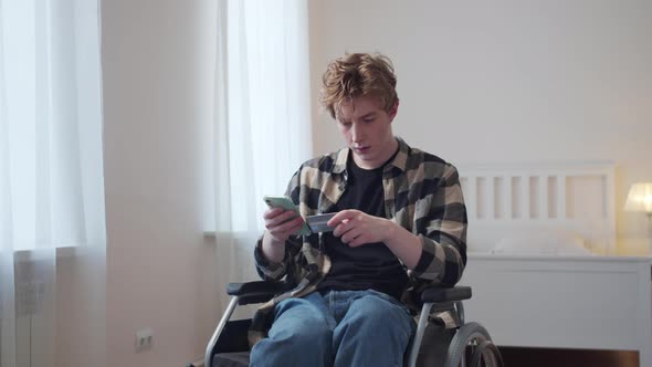 A Disabled Young Man Dials a Number From a Bank Card