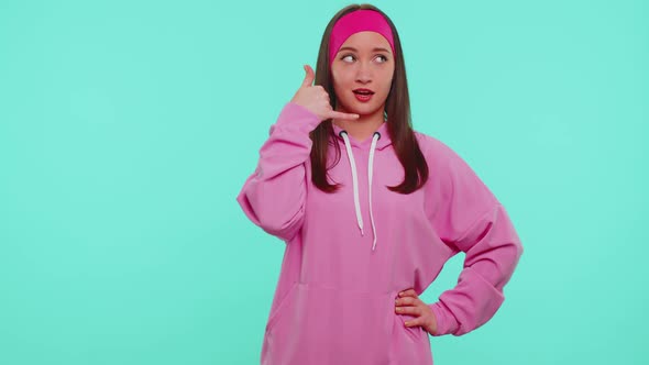 Teenager Girl in Pink Hoodie Looking at Camera Doing Phone Gesture Like Says Hey you Call Me Back