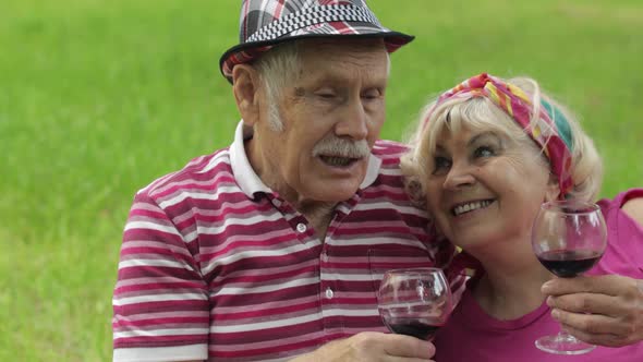 Family Weekend Picnic in Park. Active Senior Old Caucasian Couple Sit on Blanket and Drink Wine