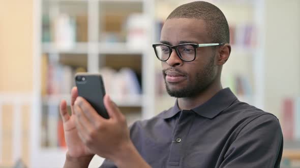 Portrait of Positive Young African Man Using Smartphone