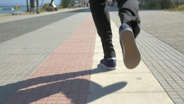 Male Feet Running on Sidewalk in Resort Town alt