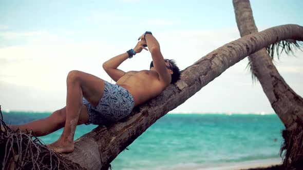 Tan Man Relaxing On Vacation Caribbean Tropical Beach. Tanned Man Lies On Palm Tree Vacation.