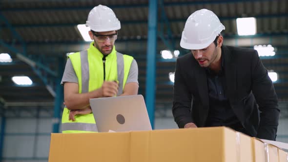 Two Factory Workers Working and Discussing Manufacturing Plan in the Factory