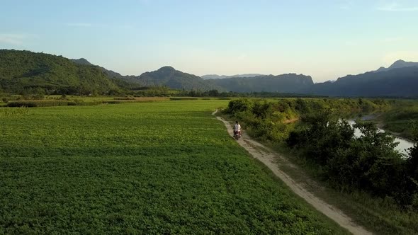 Bird Eye View Couple on Scooter at Field Against Mountains