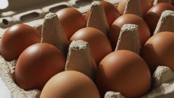 Close up of multiple eggs in a cardboard box on white surface