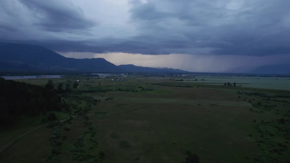 Agriculture and green fields in valley of Altai under thunderstorm sky