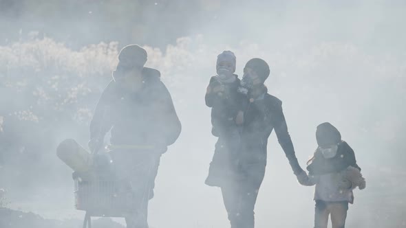 Survivor family in gas mask going through clouds of toxic smoke in desolate and burned landscape.