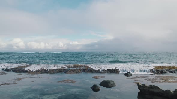 Drone view of the rocks on the shore advancing into the beautiful blue Pacific Ocean.