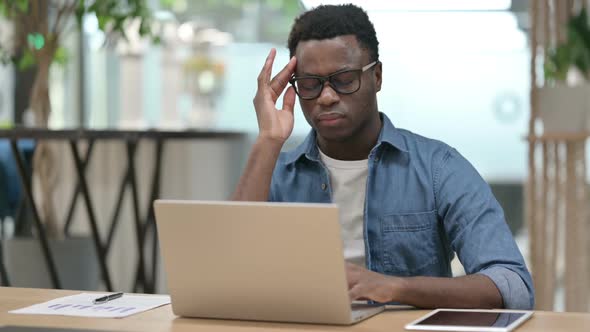 Young African Man with Headache Working on Laptop