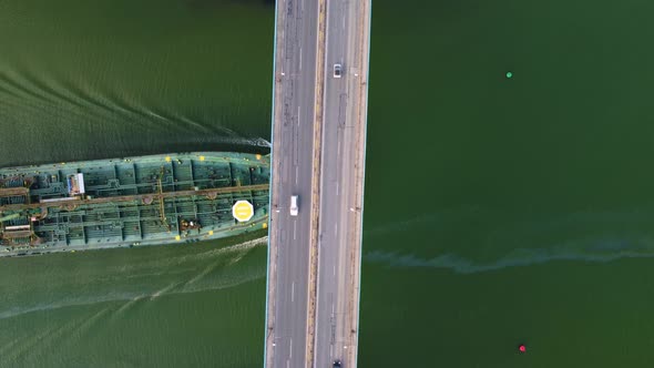 Large General Cargo Ship Tanker Bulk Carrier Passing Under a Bridge with Heavy Traffic Aerial View
