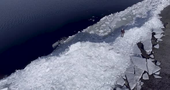 Aerial Dron View of Young Active Happy Man Staying on the Ice Glaciers Near Coastline of Winter Sea