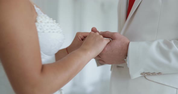 Bride and Groom Hold Hands and Look Each Other in the Eye