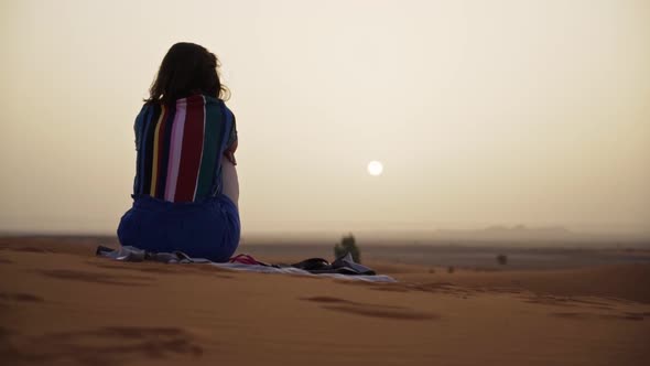 Young woman watching the desert sunset in Morocco. Saraha desert