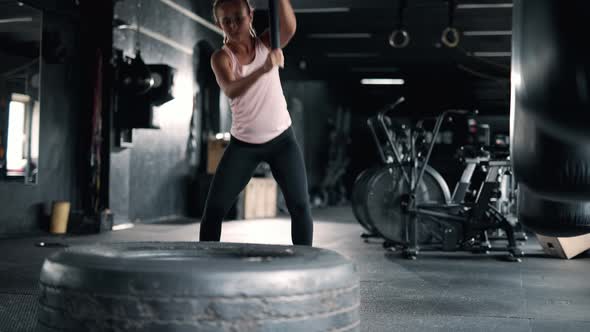A Strong Sportswoman is Hitting Huge Tire with Sledgehammer
