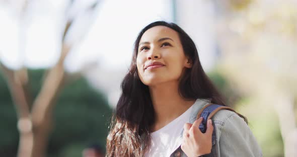 Asian woman looking around and smiling on a sunny day