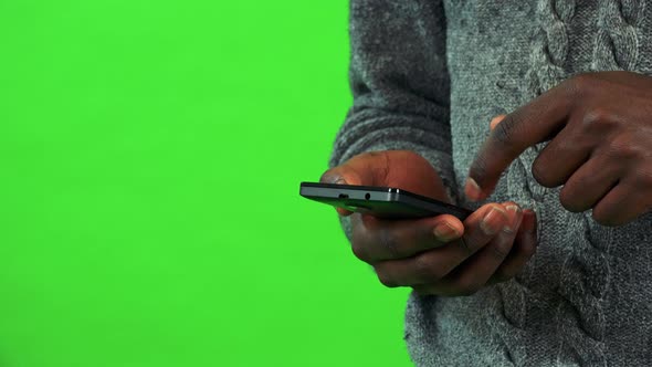 A Black Man Works on a Smartphone - Closeup - Green Screen Studio