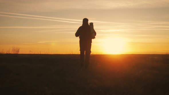 A Young Tourist Man with a Backpack Pictures Himself with a Phone. Against the Setting Sun. Slow